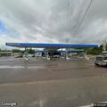 Man walking in and out of traffic near gas station