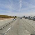 Pedestrian walking on highway shoulder with stick