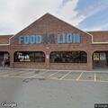 Person sitting on bench outside Food Lion in red jacket