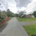 Person lying on side of road near storage building