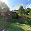 Person sitting in vehicle at abandoned house