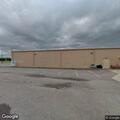 Shirtless man throwing rocks behind dollar store