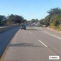 Man in gray hoodie walking along Highway 1
