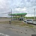 Person down on knees at gas station near blue van