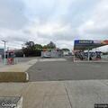 Man atop gas station canopy covering sign