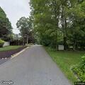 Person sitting in roadway with head near feet on Holly Road