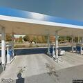 Man asleep in car at gas station with door open