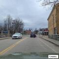 Older man walking shirtless in traffic near Crosby's