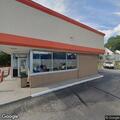 Person lying by trash can behind Dunkin' Donuts