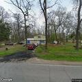 Men seen pointing rifle toward road in front yard