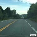 Person sitting in lane with belongings in ditch
