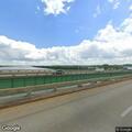 Person riding bicycle in traffic near river bridge
