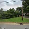 Person under shade tree drinks unknown substance at store