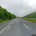 Person walking on highway near stopped vehicle