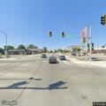 Man sitting on sidewalk near gas station at intersection