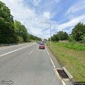 Older man in orange jumpsuit seeking ride on highway