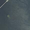 Capsized sailboat occupants safe near rocks