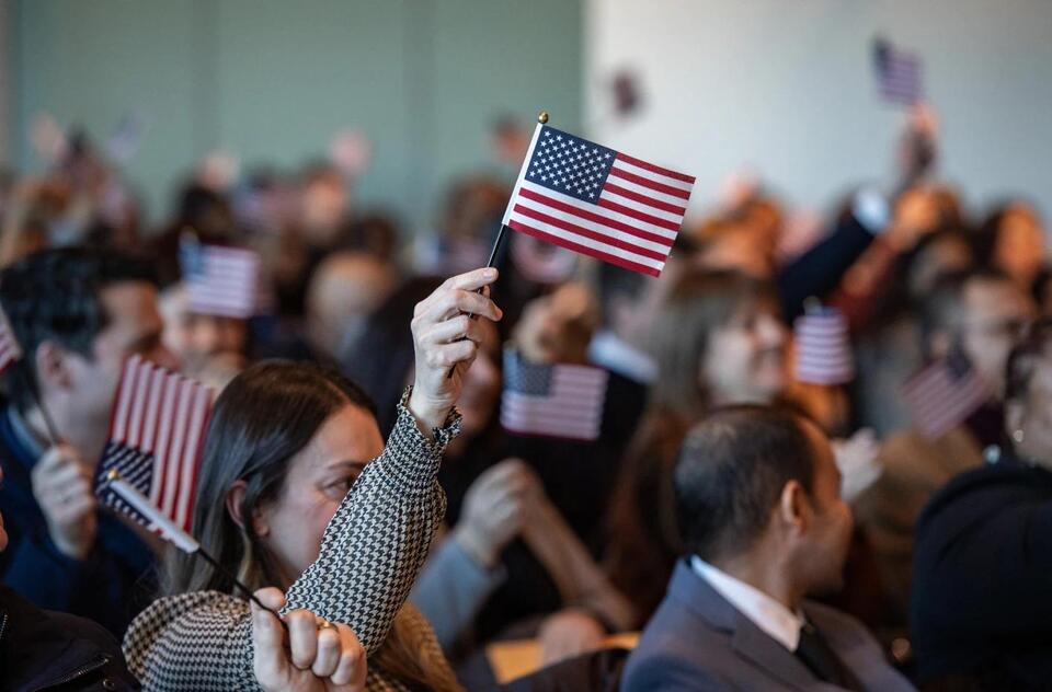 US citizen spouse holds American flag, facing visa delays.
