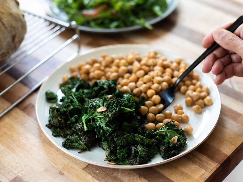 Why do leafy green vegetables interact with blood thinners?